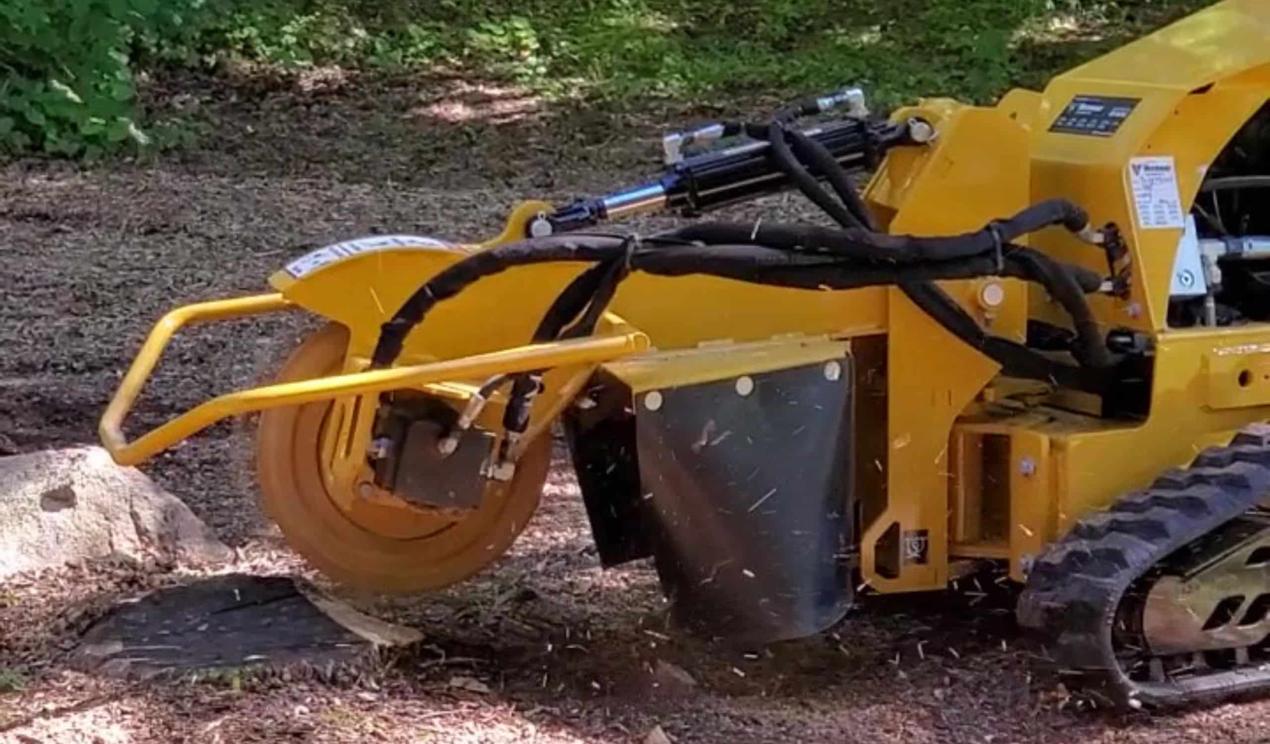 Yellow stump grinder removing tree stump outdoors